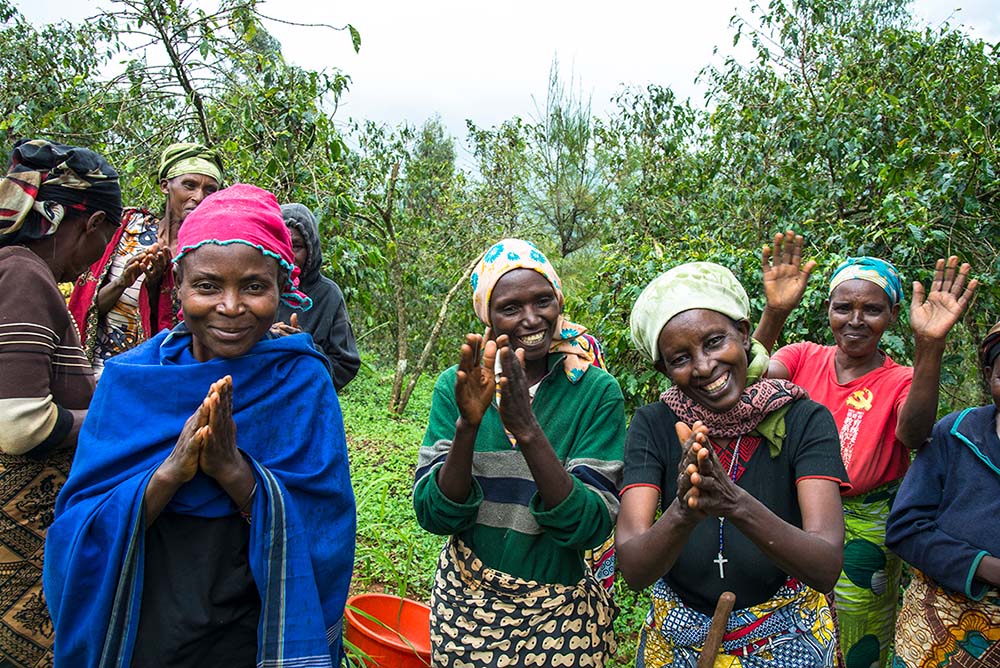 women smiling while taking a break from harvesting coffee beans